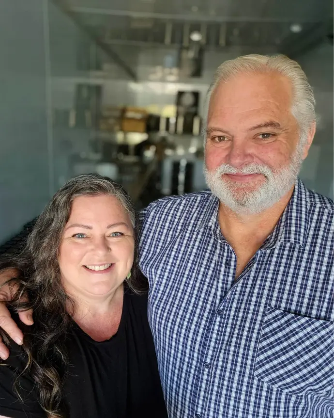 An image of Debbie and Graeme, with the Wild West Gourmet kitchen softly blurred in the background. 